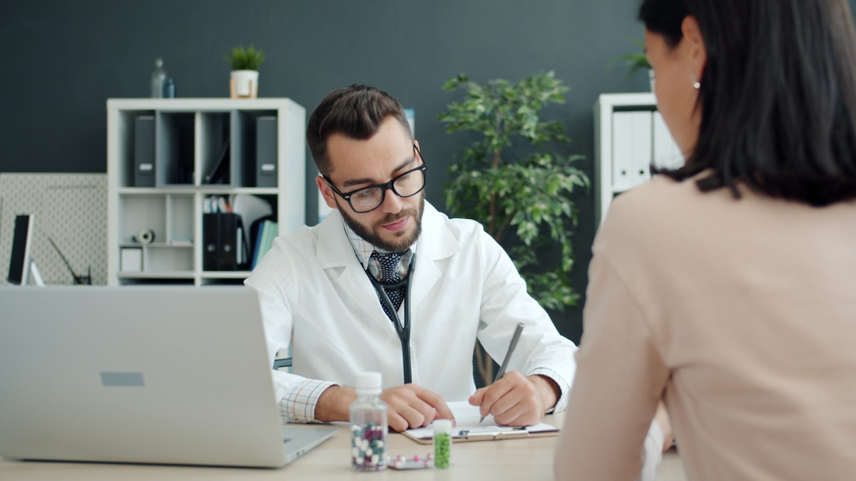 A clinician consulting with a female patient in a clinic exam room