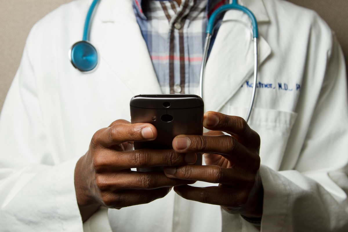 Doctor Holding Cell Phone. Cell phones and other kinds of mobile devices and communications technologies are of incre...